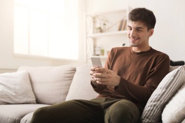 Evde akıllı telefonu olan genç bir adam.