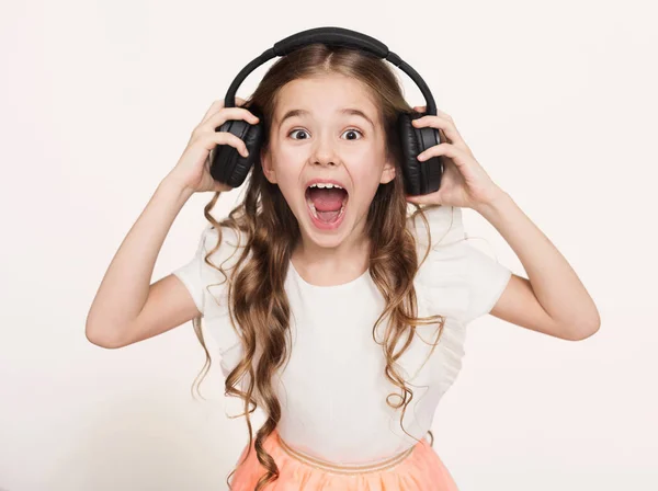 Menina feliz ouvir música em fones de ouvido, fundo branco — Fotografia de Stock