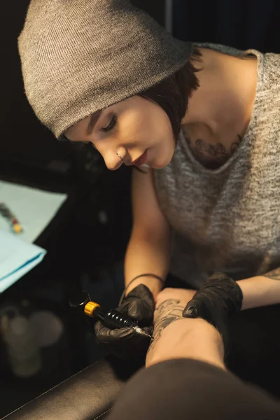 男性の腕に刺青をしている若い女性彫師 — ストック写真