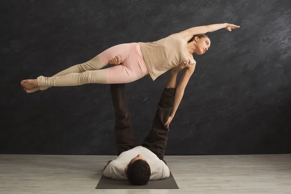 Pareja joven practicando acroyoga en alfombra juntos — Foto de Stock