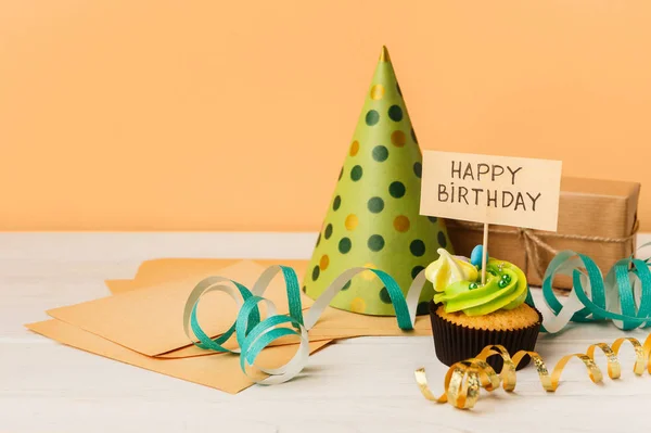 Heerlijke cupcake en gift op gele achtergrond — Stockfoto