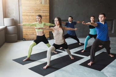 Genç kadın ve erkekler yoga sınıfındaki germe egzersizleri yapıyor