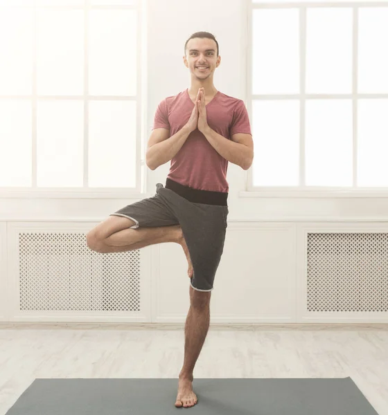 Ung man utbildning yoga i tree pose — Stockfoto