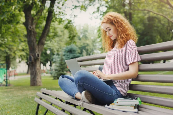 Щасливий студент використовує ноутбук у парку — стокове фото