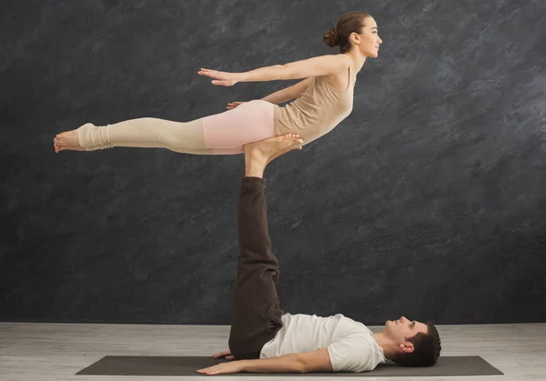 若いカップルが一緒にマットで acroyoga の練習 — ストック写真