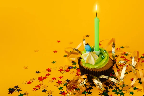 Urodzinowa babeczka ze świecą na żółtym tle — Zdjęcie stockowe