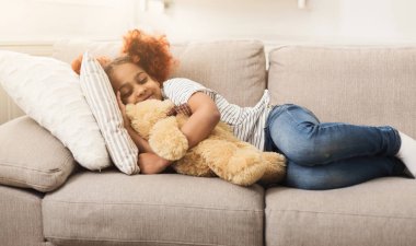Küçük mutlu Afrikalı-Amerikalı kız evde kanepede uyuyor