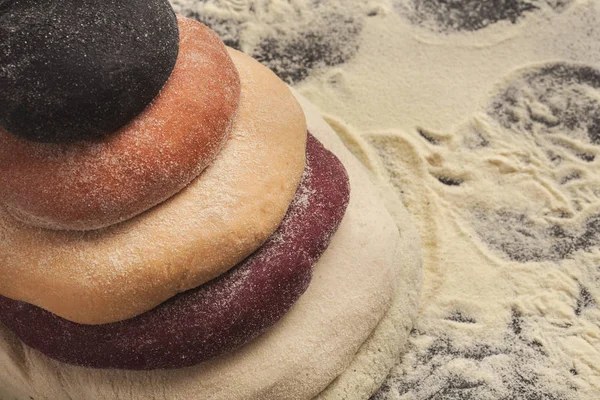 Цветное свежее тесто для макарон на черном столе — стоковое фото