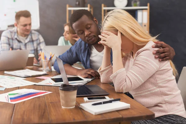 Man supporting woman reading bad news in email