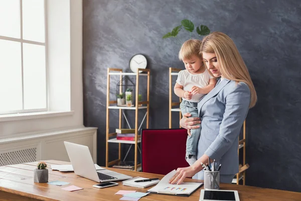 Junge Mutter hält Baby beim Lesen von Dokumenten — Stockfoto