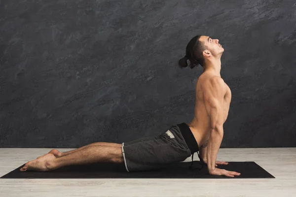 Hombre practicando yoga en fondo gris — Foto de Stock