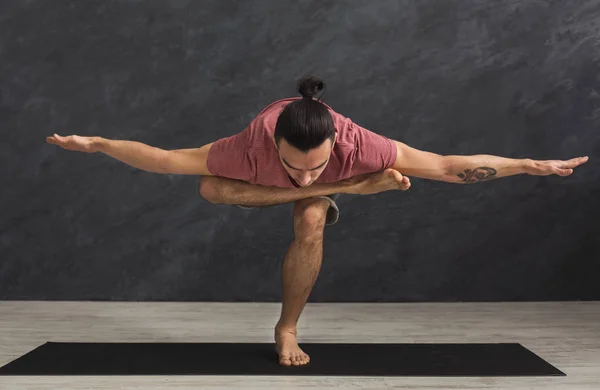 Молодой гибкий человек, практикующий йогу в спортзале — стоковое фото