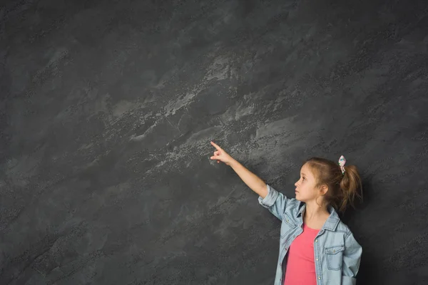 Kleines Mädchen zeigt Finger nach oben vor grauem Hintergrund — Stockfoto