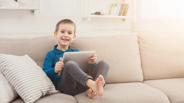 Маленький мальчик с цифровой планшет на диване дома — стоковое фото