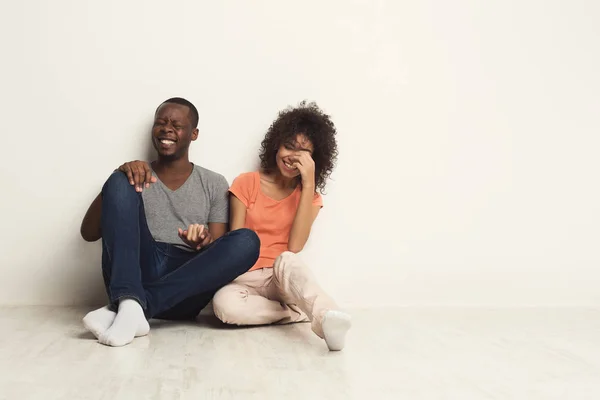 คู่รักชาวแอฟริกัน-อเมริกันกอดกัน นั่งอยู่บนพื้น — ภาพถ่ายสต็อก