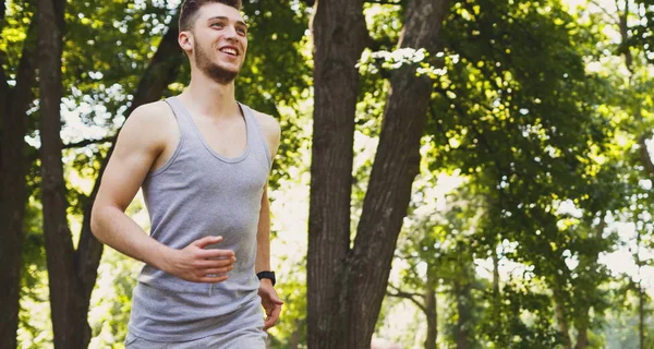 Jeune homme courant dans un parc vert, espace de copie — Photo