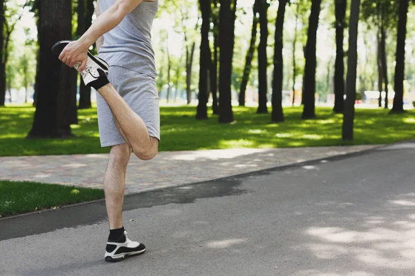 Hombre de fitness irreconocible estirando las piernas al aire libre —  Fotos de Stock