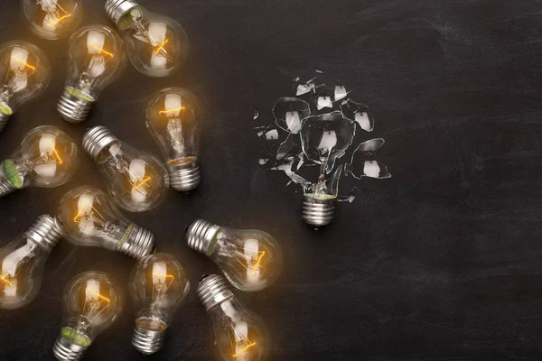 Whole and broken light bulbs on black background — Stock Photo, Image