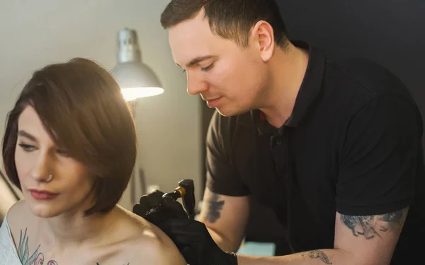 Tattoo artist working with needle on clients body