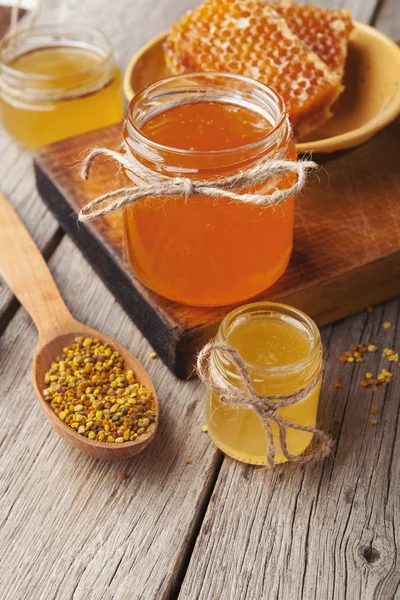 Golden honeycombs and honey jars on wooden table — Stock Photo, Image