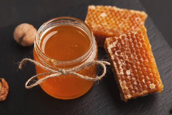 Golden honeycombs and honey jar, closeup — Stock Photo, Image