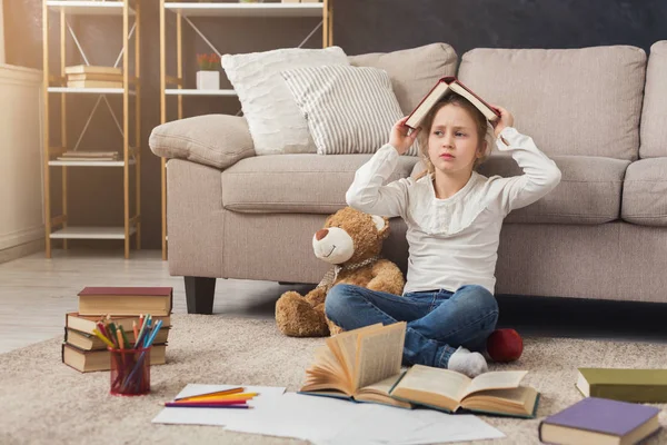 Pequeña niña leyendo libro mientras está sentada en la alfombra —  Fotos de Stock