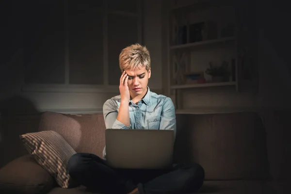 Уставшая женщина с ноутбуком в темном офисе копировального пространства — стоковое фото