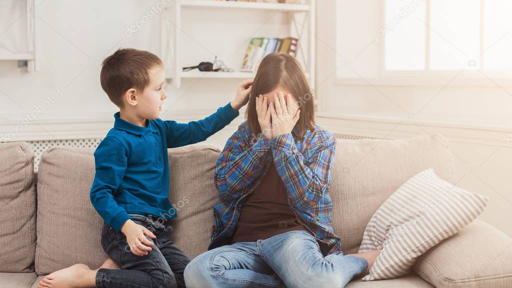Boy calming down his crying sister at home