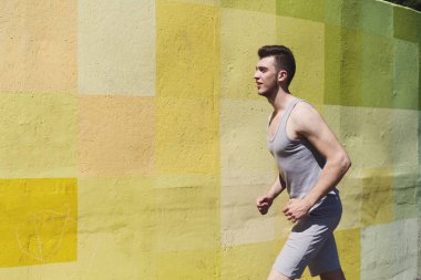 Yorgun kaslı erkek atlet parlak renkli grafiti duvara, kopya alanı çalışan yan görünüm
