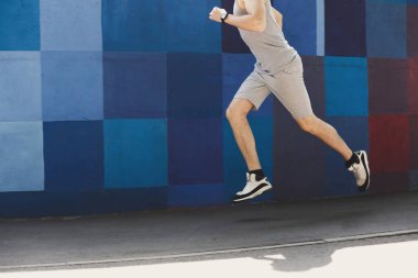 Parlak mavi duvara koşan tanınmayan adam