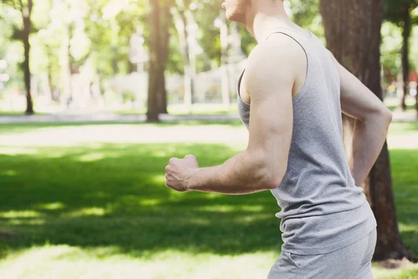 Young man running in green park, copy space