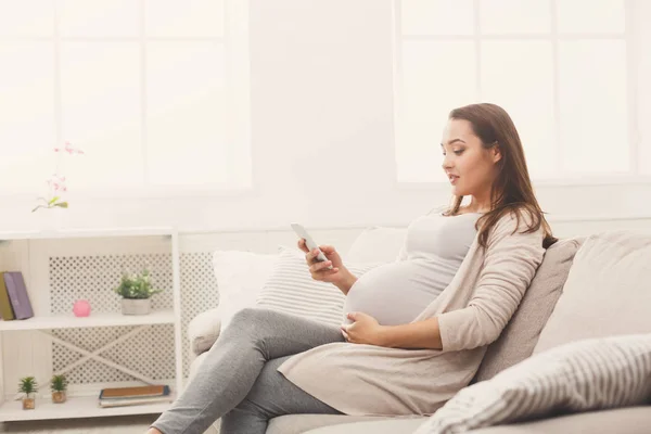 Счастливая беременная женщина с помощью смартфона — стоковое фото