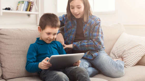 Twee kinderen met gadget op Bank thuis — Stockfoto