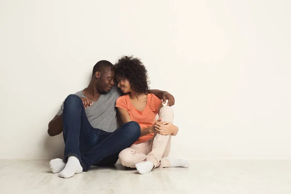 Casal afro-americano abraçando, sentado no chão — Fotografia de Stock