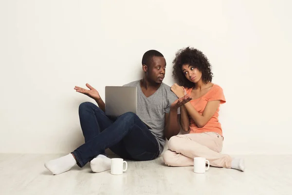 Casal sério usando laptop, sentado no chão — Fotografia de Stock