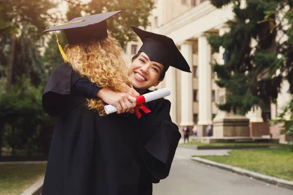 Pareja de estudiantes abrazándose en su día de graduación — Foto de Stock