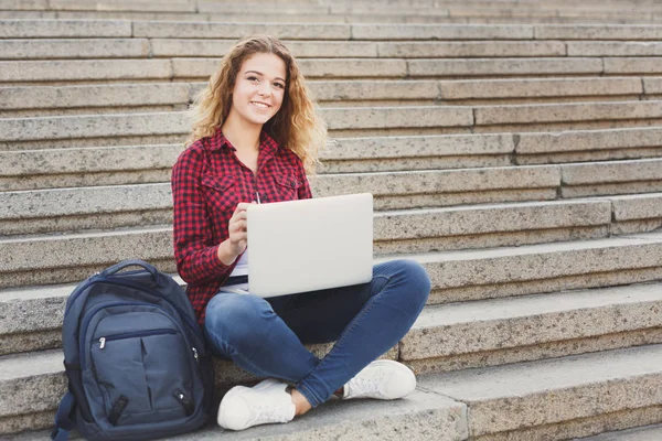 Mujer estudiante sentada en las escaleras y trabajando con el ordenador portátil — Foto de Stock