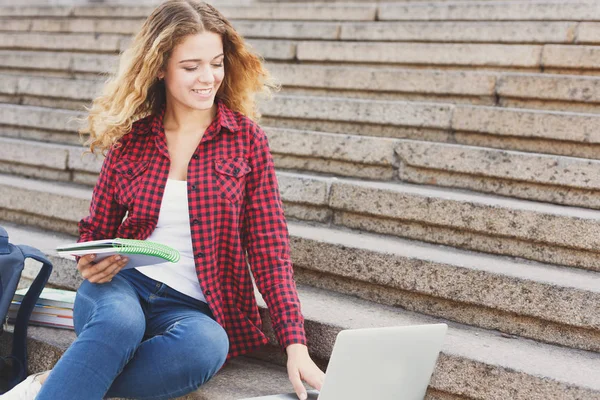 Student dívka sedí na schodech, čtení poznámek a používání lapt — Stock fotografie