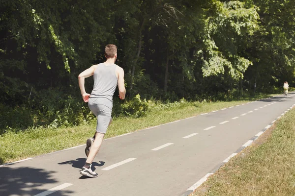 Jovem jogging homem na esteira no parque, espaço cópia — Fotografia de Stock