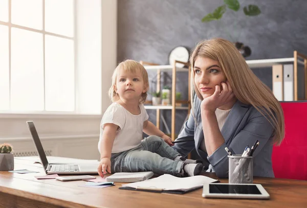 Joven madre sosteniendo bebé mientras escribe notas — Foto de Stock