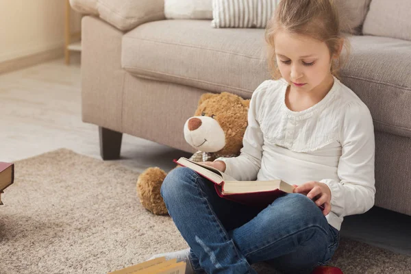 Malé dítě ženského pohlaví, čtení knihy, zatímco sedí na koberci — Stock fotografie