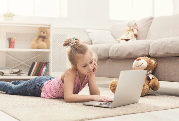 Unatkozó kislány csinál házi feladatot-ra laptop — Stock Fotó