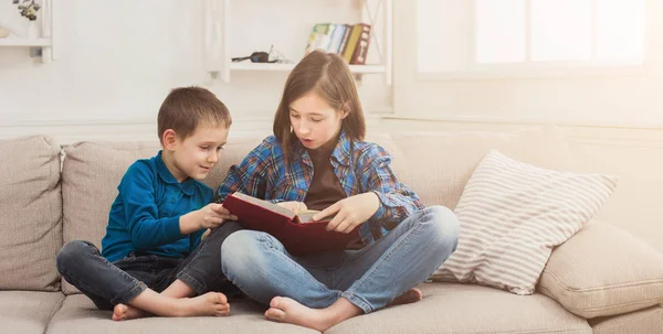 Young girl reading book for her brother — Stock Photo, Image