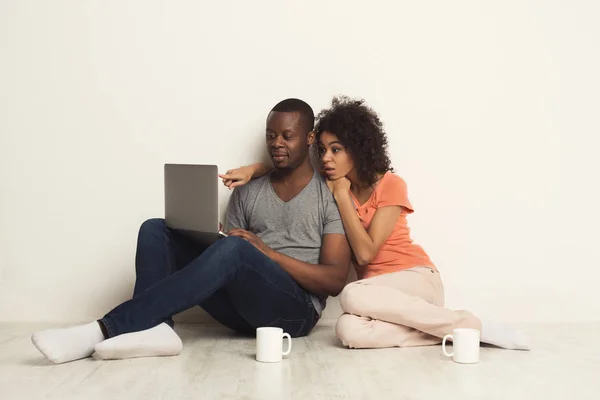 Σοκαρισμένος ζευγάρι χρησιμοποιώντας φορητό υπολογιστή, κάθεται στο πάτωμα — Φωτογραφία Αρχείου