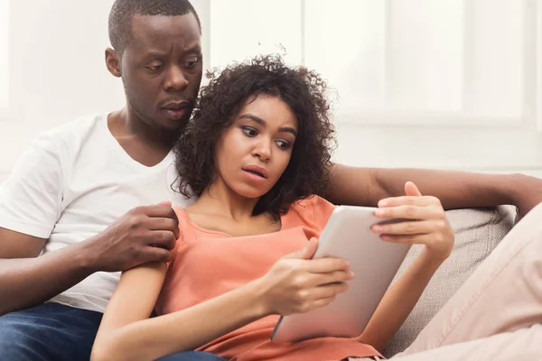 デジタル タブレット オンライン ショッピングや 新しいアパートに置いてあるソファにソーシャルネットワー キングを使用して深刻なアフリカ系アメリカ人のカップルをコピー スペース — ストック写真