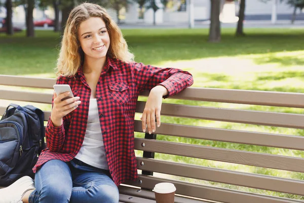 Sonriendo mensajes de texto jóvenes en el teléfono inteligente al aire libre — Foto de Stock