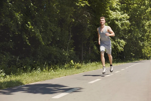 Junger Mann joggt auf Laufband im Park — Stockfoto