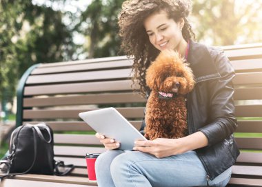 Tablet ve Şehir Parkı, küçük köpek ile gülümseyen genç kadın