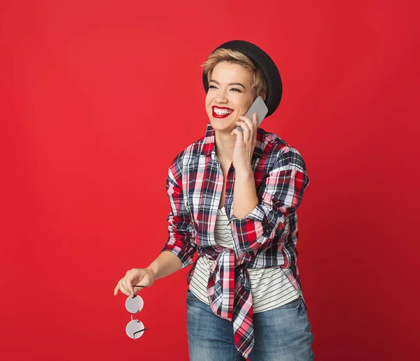Смеющаяся девушка разговаривает по мобильному на красном фоне — стоковое фото