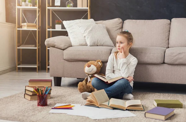 Little female child reading book while sitting on the carpet — Stock Photo, Image